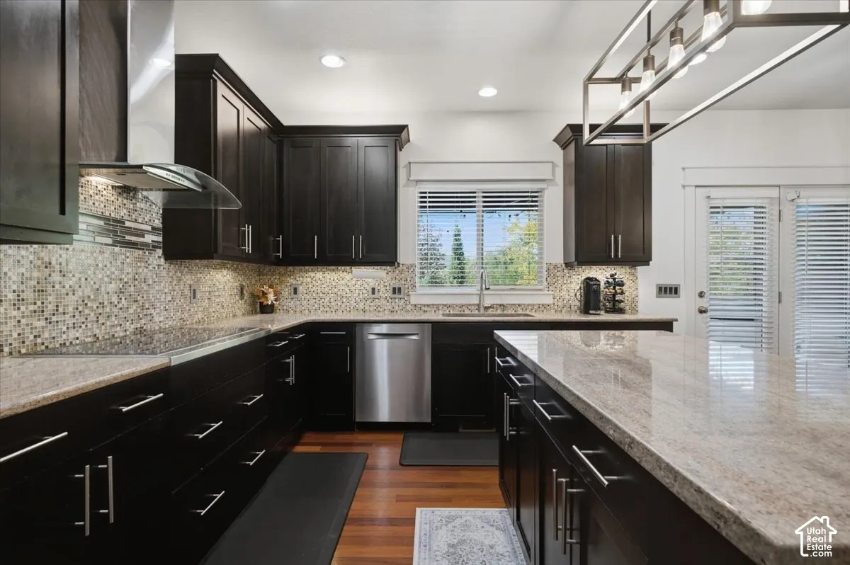 Kitchen featuring dark wood cabinetry, light-toned countertops, a mosaic tile backsplash, stainless steel appliances, and wood-finish flooring