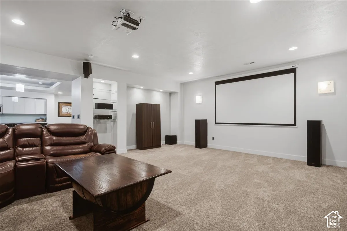 Recessed lighting, mounted projector, large projection screen, wall-mounted speakers, and light-toned carpet flooring