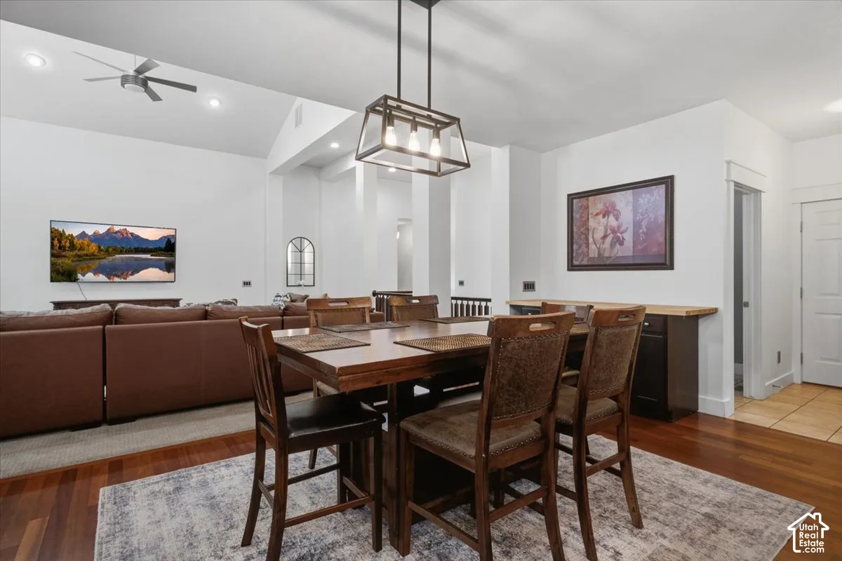 Vaulted ceiling with recessed lighting and ceiling fan, wood-finish flooring, built-in cabinetry with wood countertop, and a contemporary linear chandelier