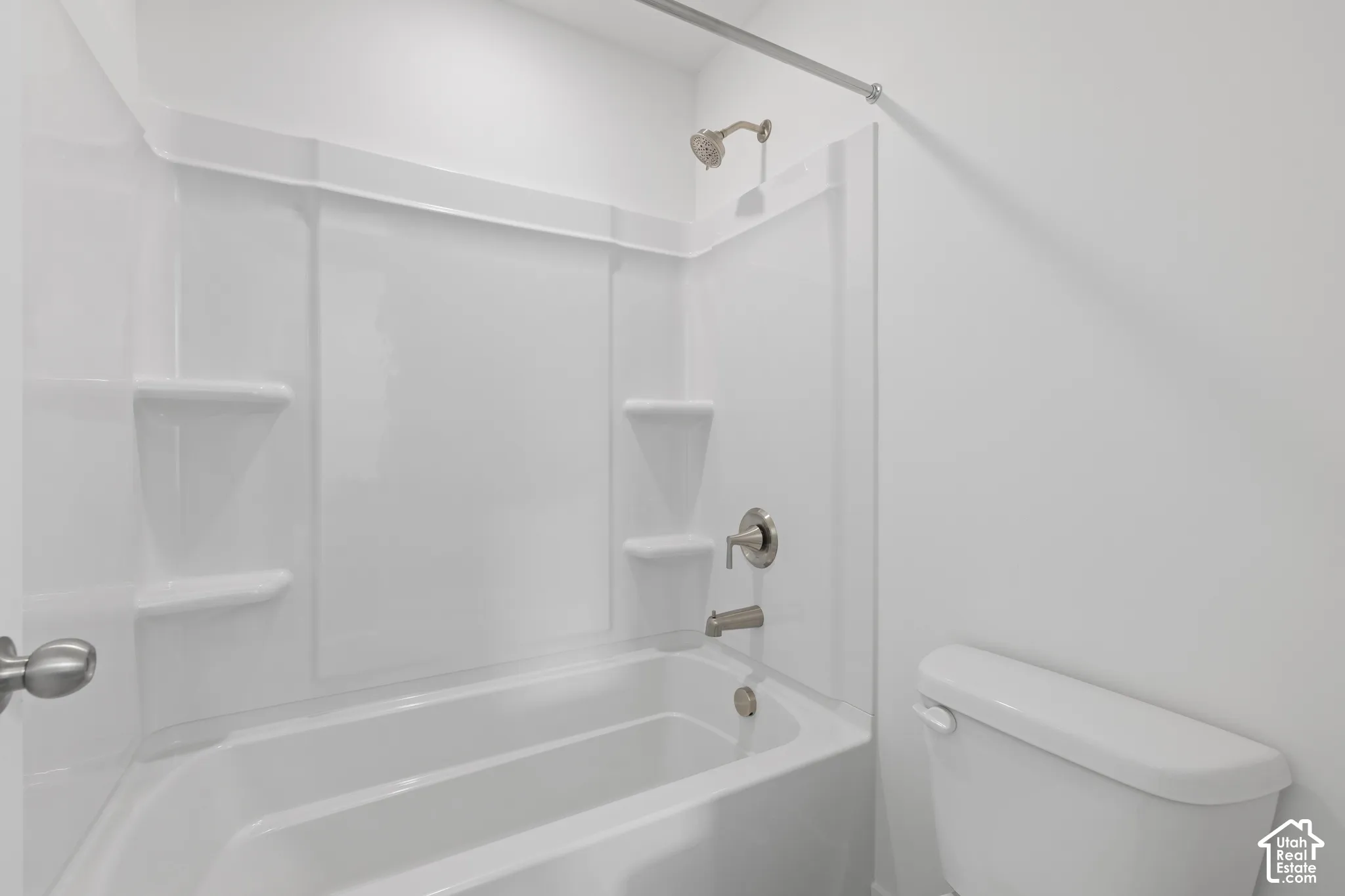 White bathtub with integrated shelving, brushed nickel fixtures, and a shower/tub combination
