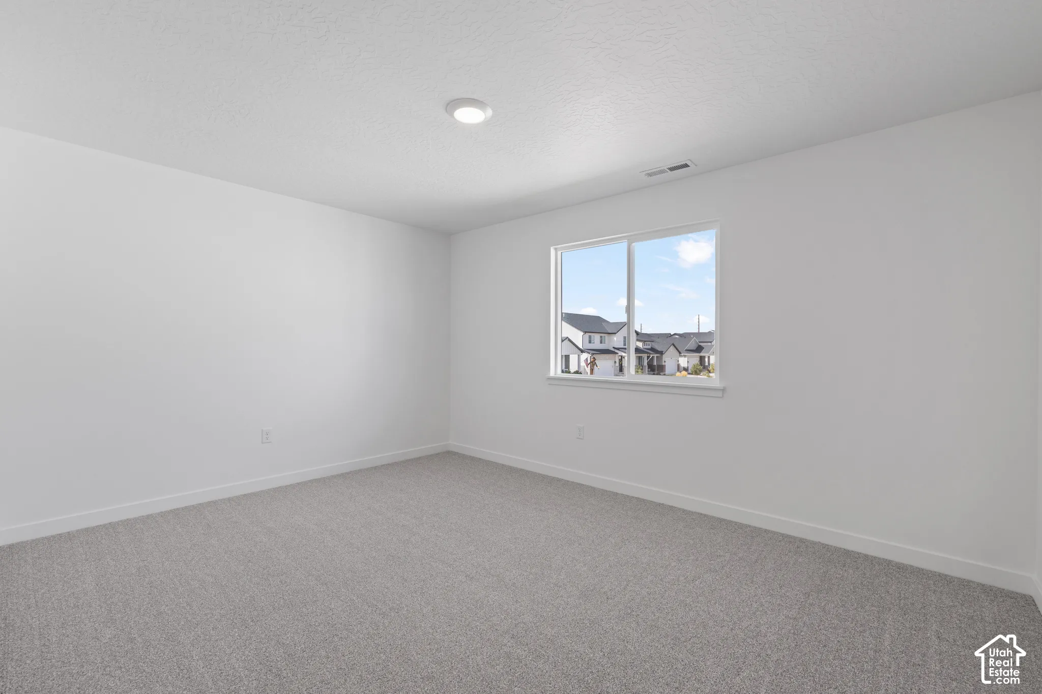 Recessed ceiling lighting, light gray wall-to-wall carpeting, and a double-pane window