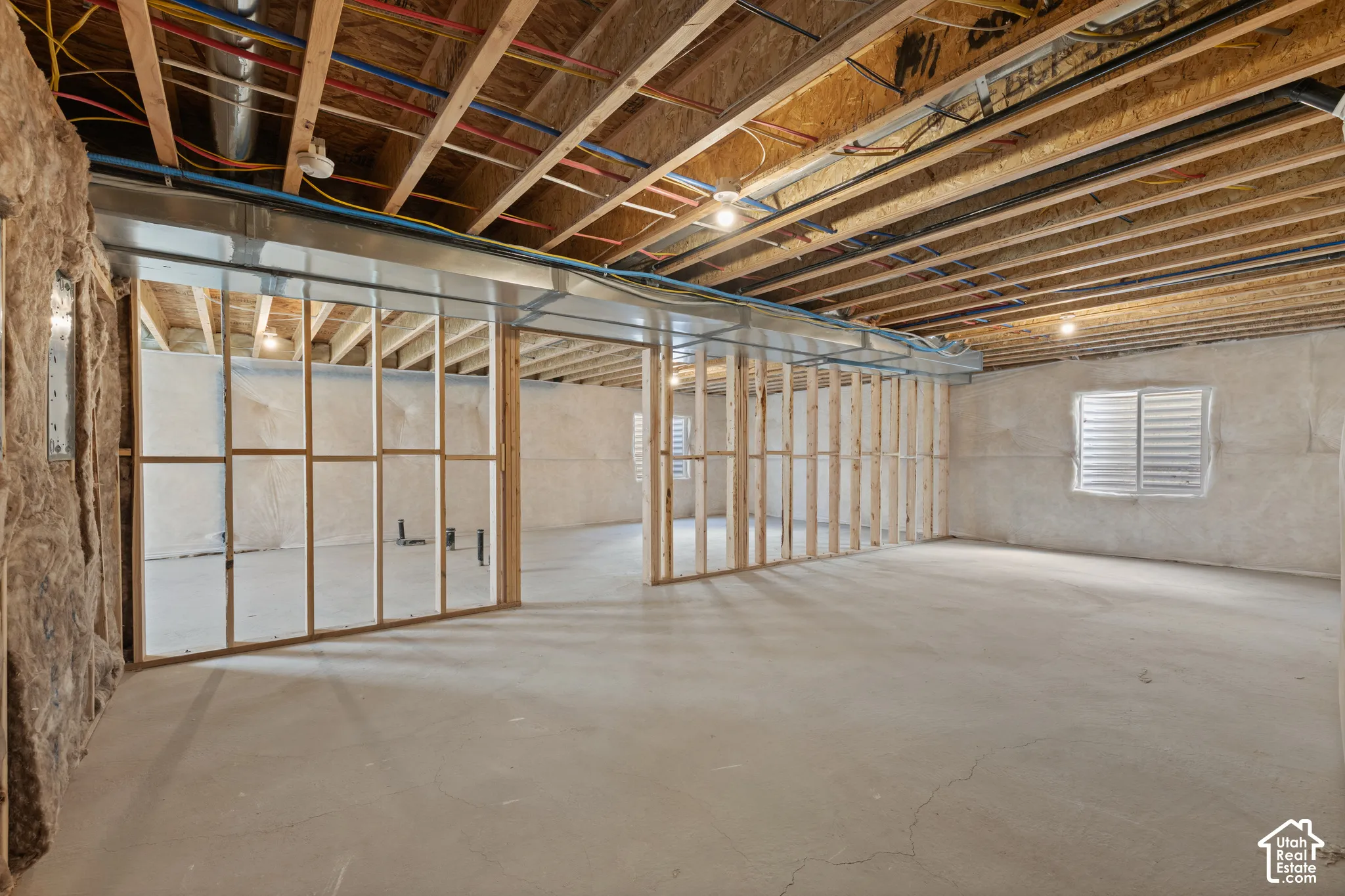 Unfinished basement featuring exposed wood joists, concrete flooring, and framed interior walls