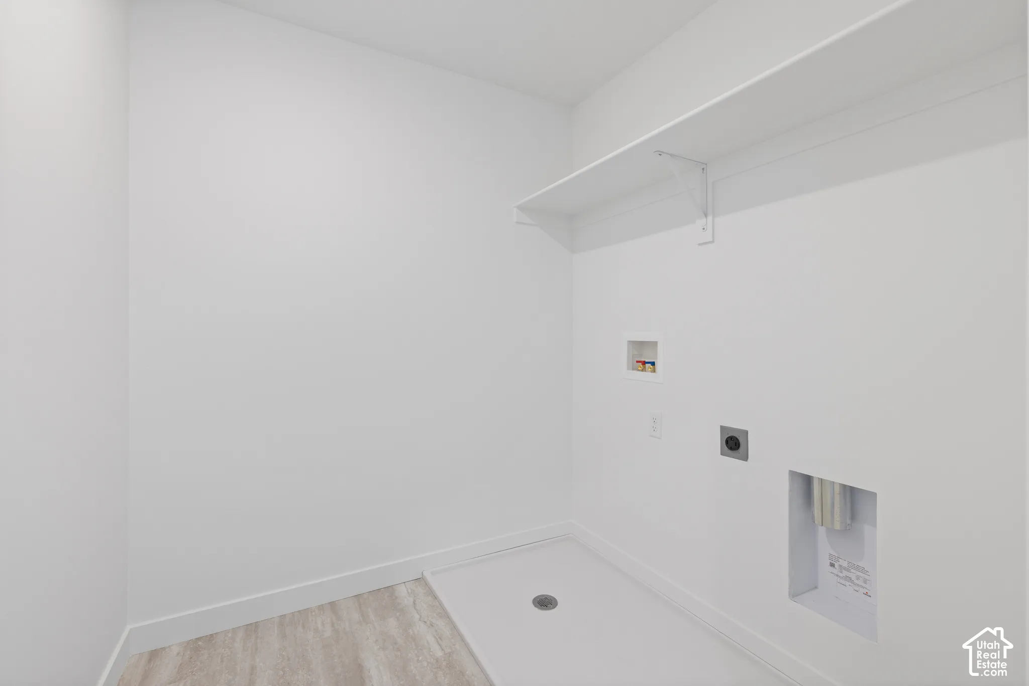 Utility space featuring a built-in shelf, prepped connections for appliances, and wood-finish flooring
