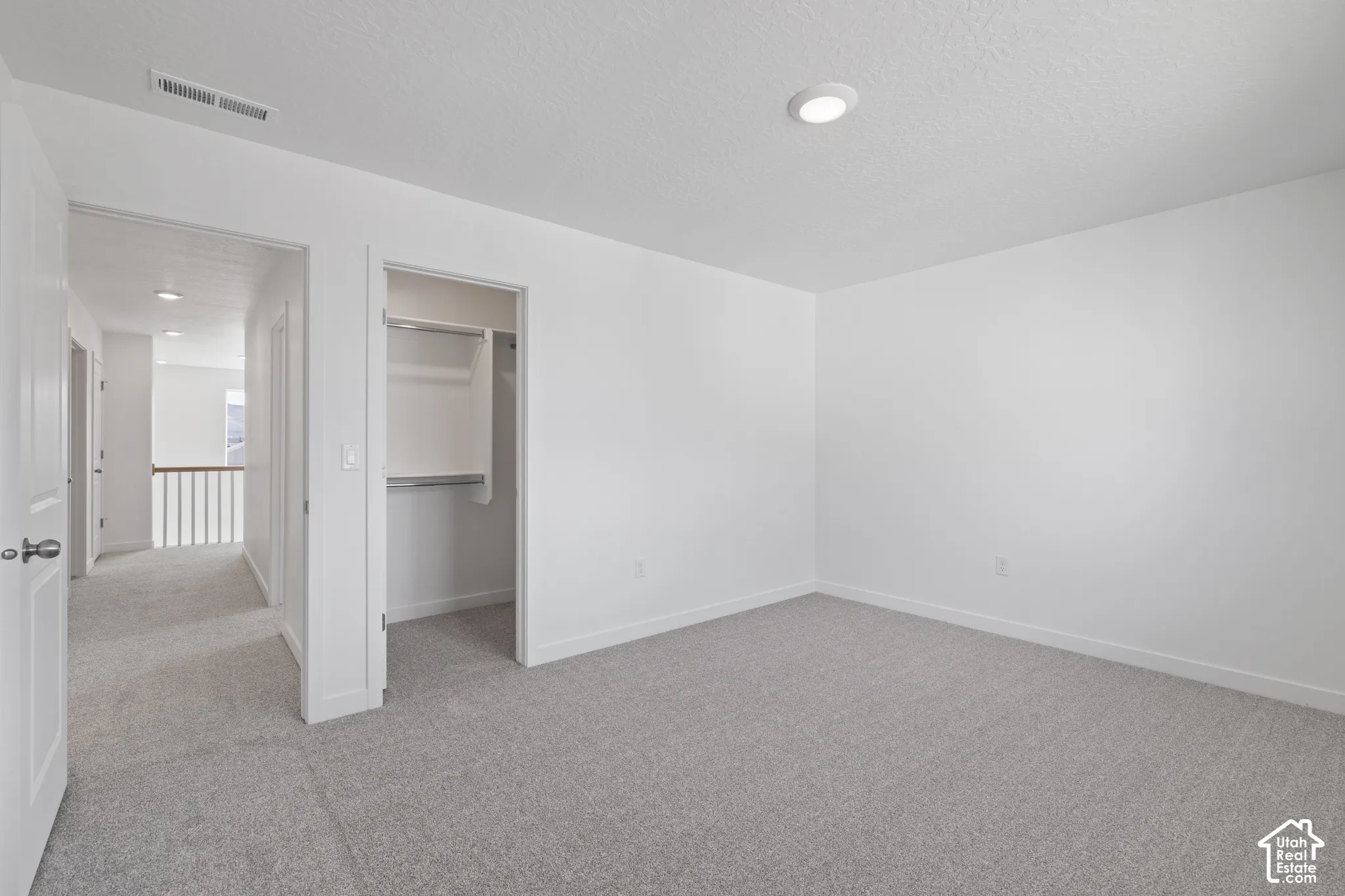 Neutral-toned carpeting, recessed ceiling lighting, and a built-in closet with shelving and hanging rods