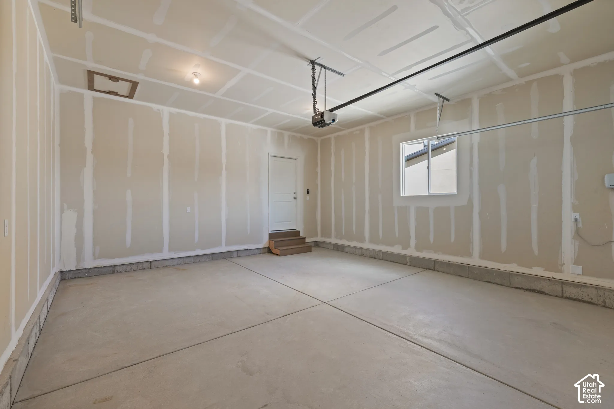 Spacious garage with concrete flooring, automatic garage door opener, interior access door, and window