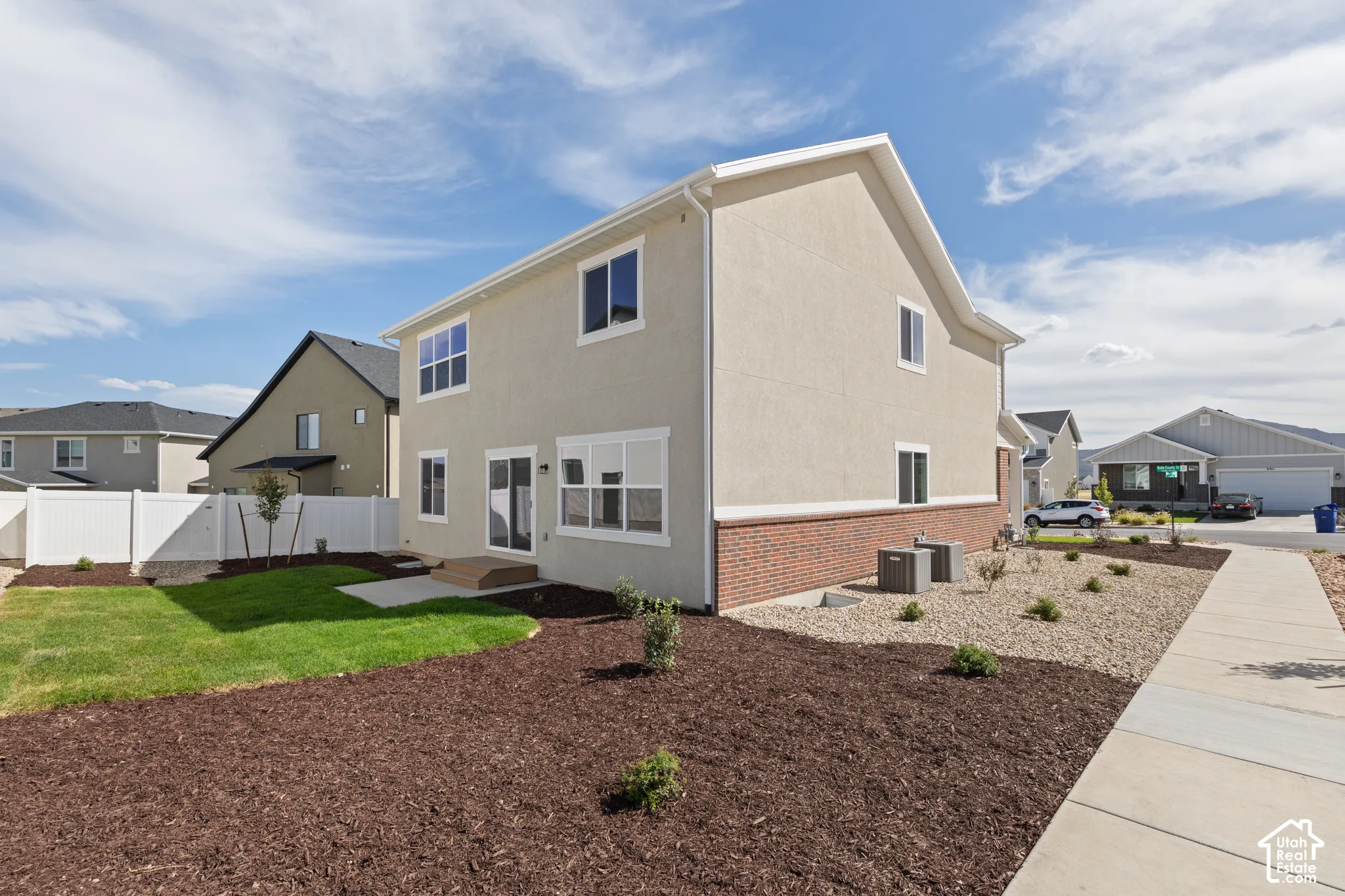 Stucco exterior with a brick foundation, featuring multiple windows and a sliding glass door