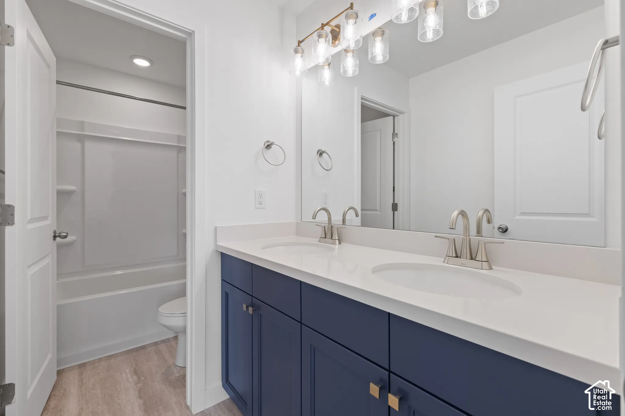 Dual vanity with a white countertop and navy cabinetry, brushed nickel faucets, and a multi-bulb light fixture