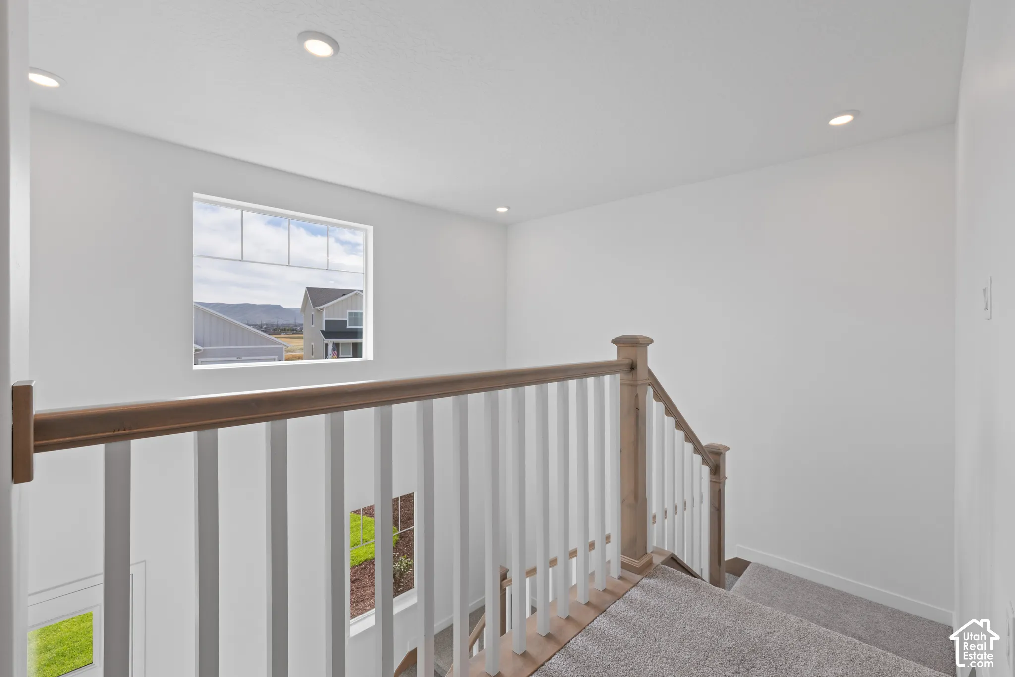 Carpeted staircase with wood-finish handrail and white balusters