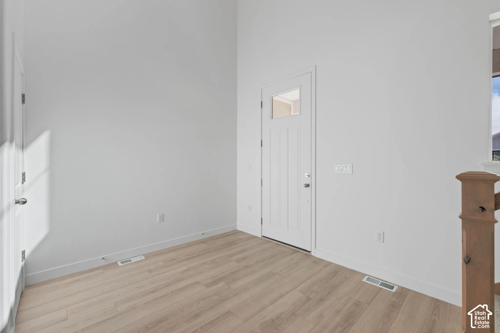 Entryway with wood-finish flooring, white walls, and a door featuring a glass pane