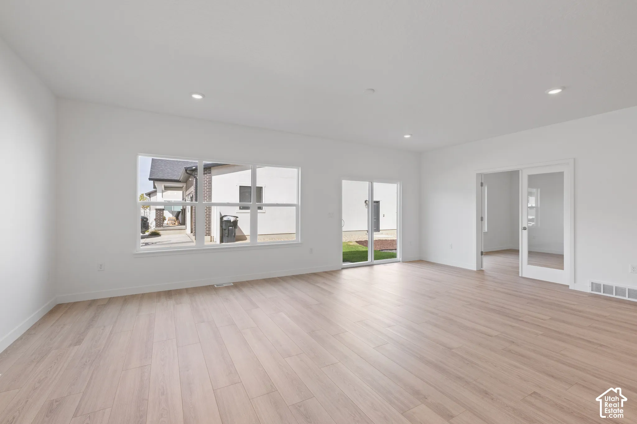 Expansive room featuring light wood-finish flooring, recessed lighting, and a large multi-pane window
