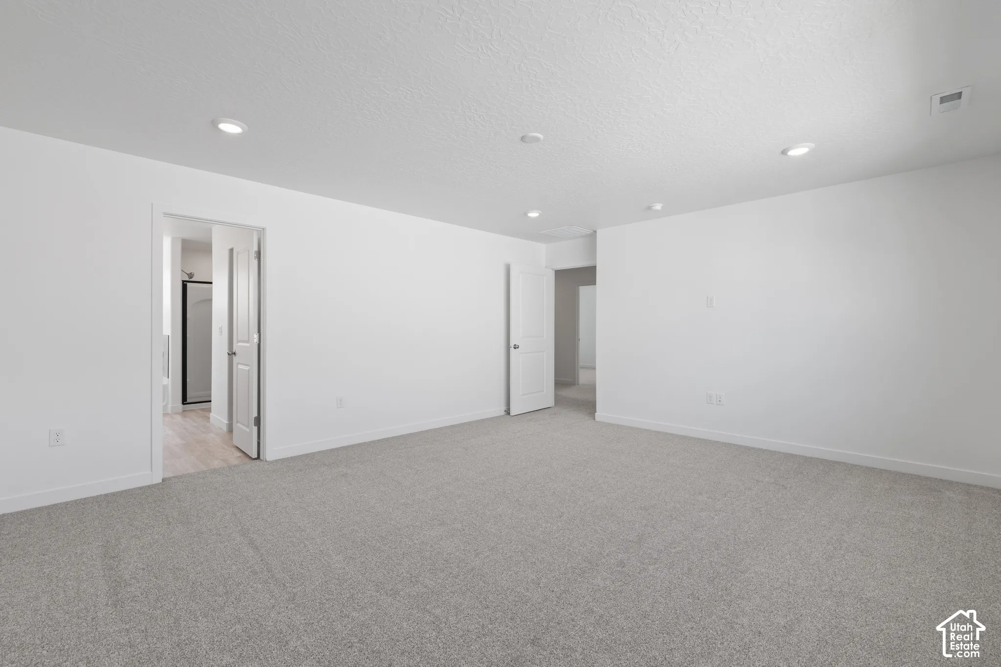 Spacious interior with neutral gray carpet and white walls