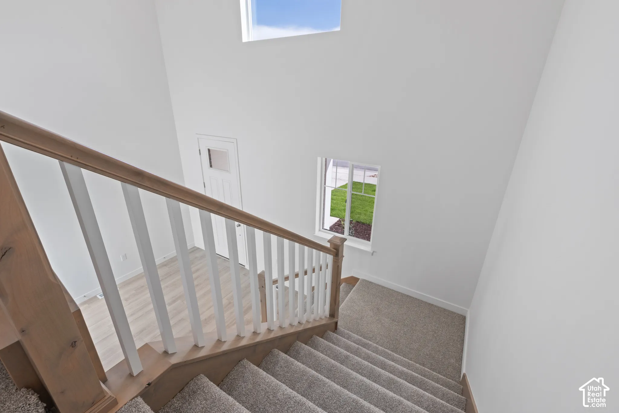 Staircase featuring wood-finish handrails, white balusters, and carpeted treads