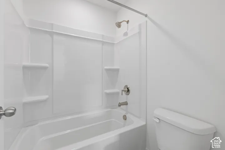 White bathtub with integrated shelving, brushed nickel fixtures, and a shower/tub combination