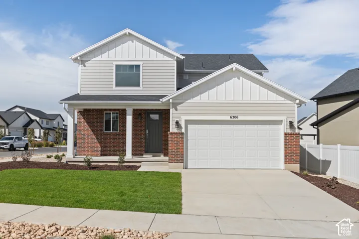 Two-story residence featuring a brick and siding exterior, a covered front porch, and an attached two-car garage