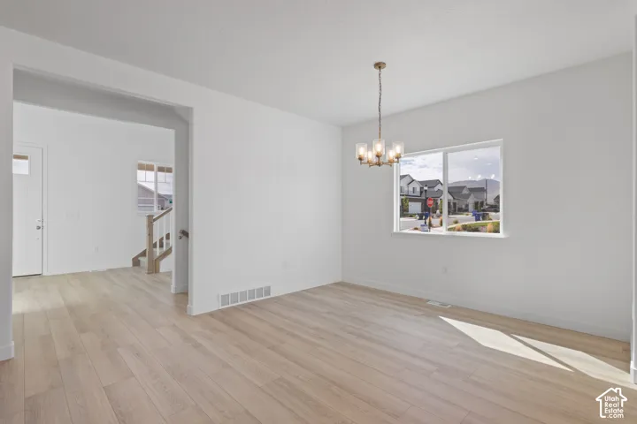 Light wood-finish flooring, white painted walls, and a modern brass chandelier with clear glass shades