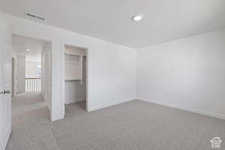 Neutral-toned carpeting, recessed ceiling lighting, and a built-in closet with shelving and hanging rods