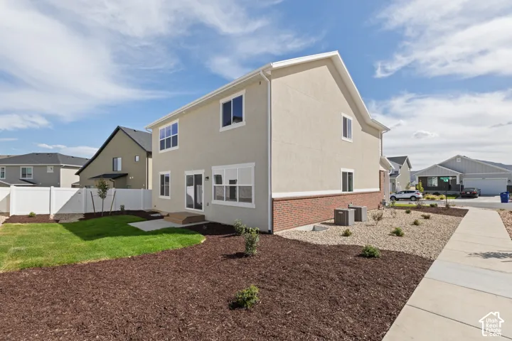 Stucco exterior with a brick foundation, featuring multiple windows and a sliding glass door