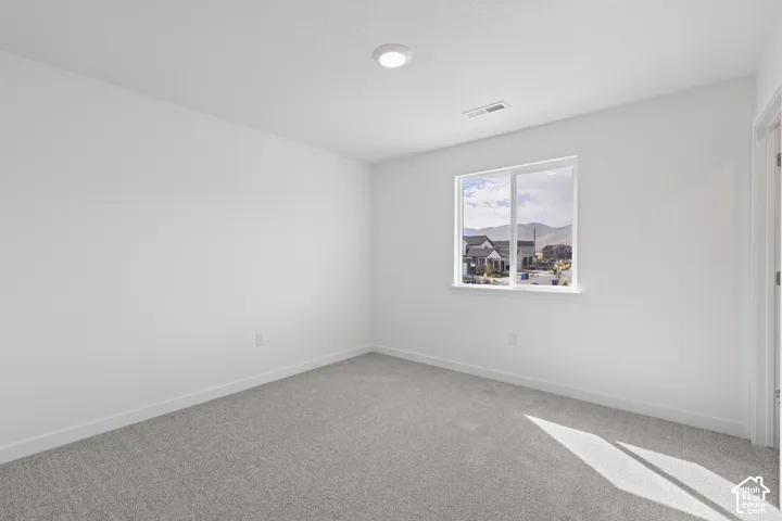 Neutral wall color, light gray carpeting, recessed ceiling lighting, and a single window