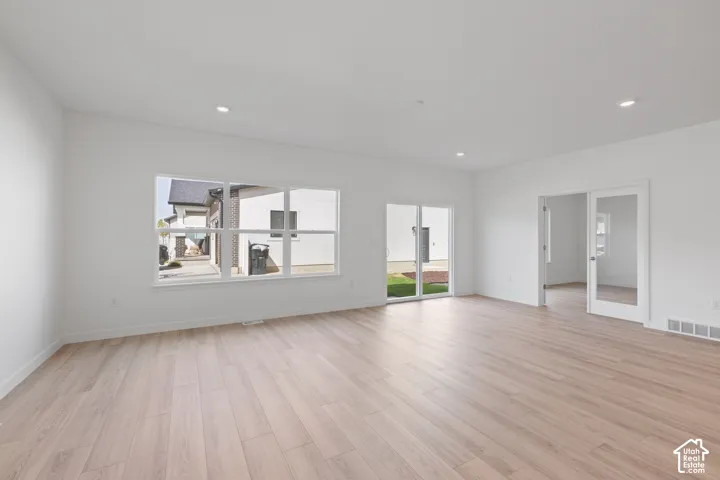 Expansive room featuring light wood-finish flooring, recessed lighting, and a large multi-pane window