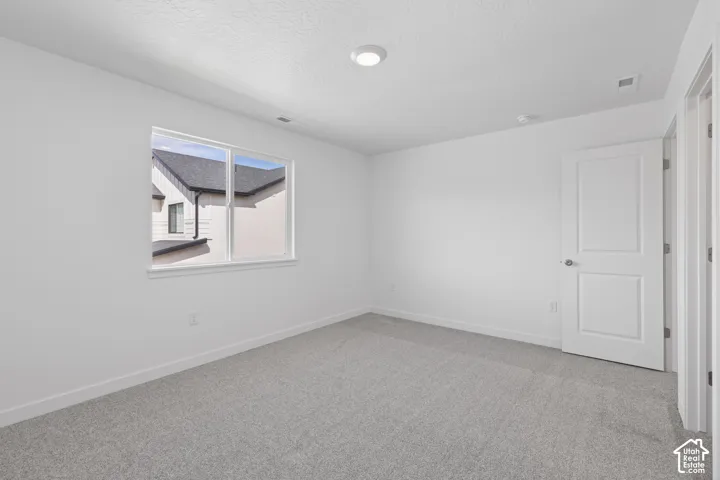 Neutral color palette, window with white trim, gray carpeting, white walls, flush mount lighting