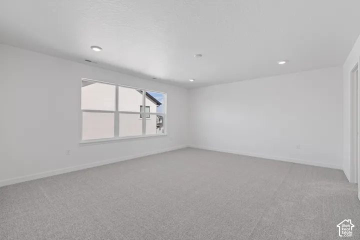Recessed lighting illuminates this room featuring light gray carpeting and a multi-pane window
