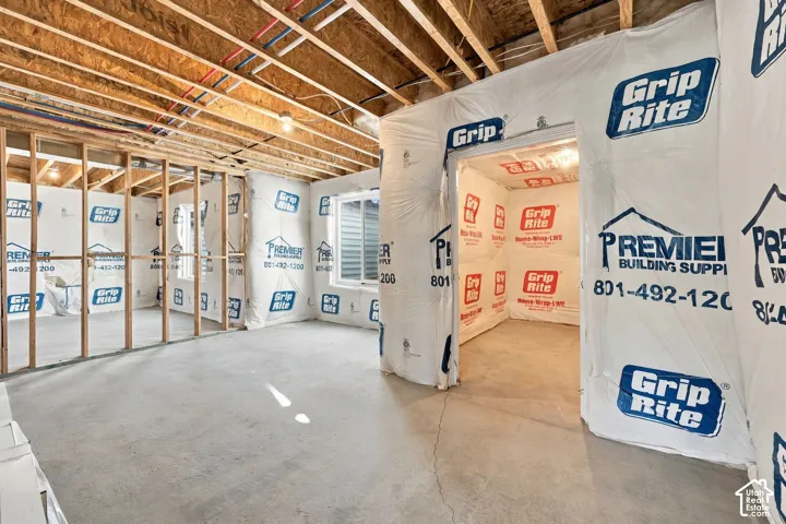 Unfinished basement space featuring exposed wood framing, exposed ceiling joists, and concrete flooring