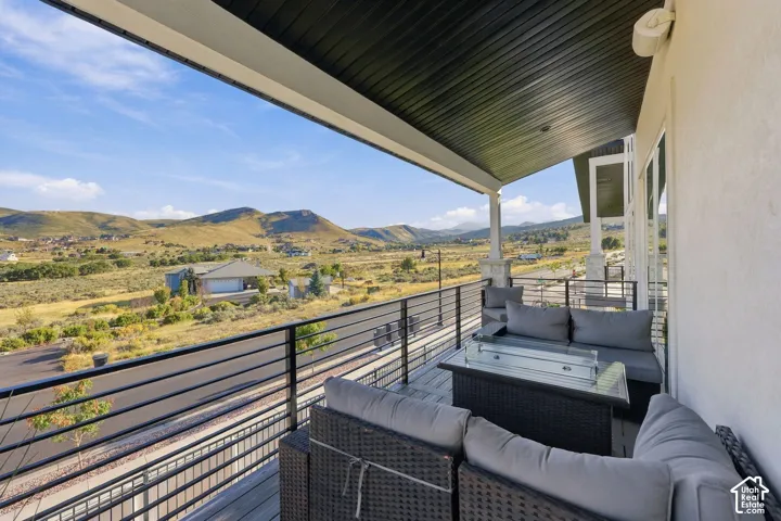 Covered outdoor balcony with a wood-finish deck, contemporary metal railing, and stucco exterior