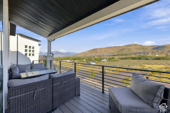 Covered outdoor deck with wood-finish flooring, black metal railings, and a white support pillar with stone-finish detailing