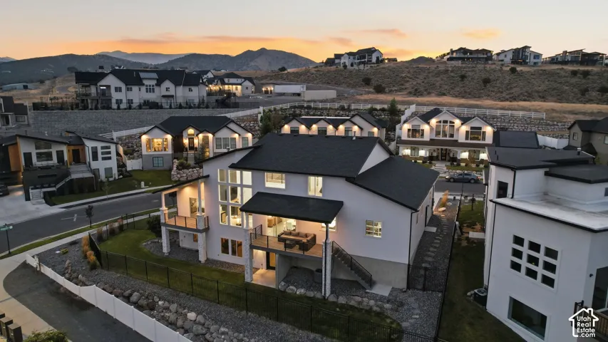 Modern architecture with a multi-level exterior, an upper-level balcony, a ground-level covered patio, and a fully fenced yard