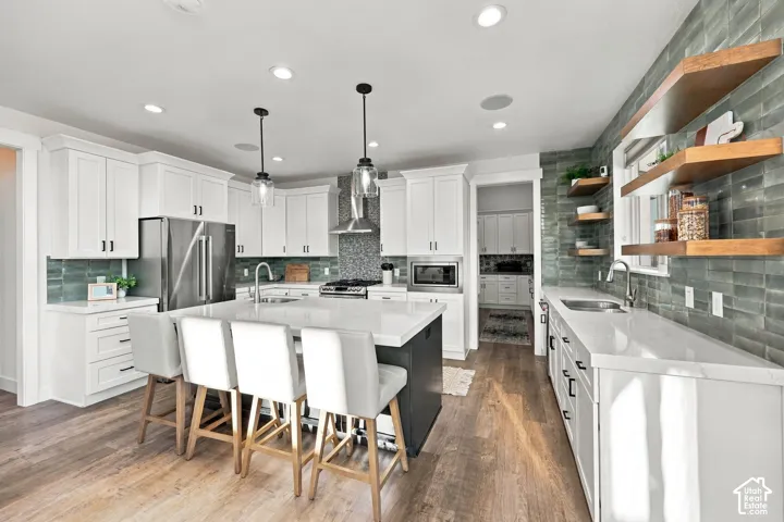 Kitchen with wood-finish flooring, white cabinetry, a large central island, recessed lighting, and a subway tile backsplash
