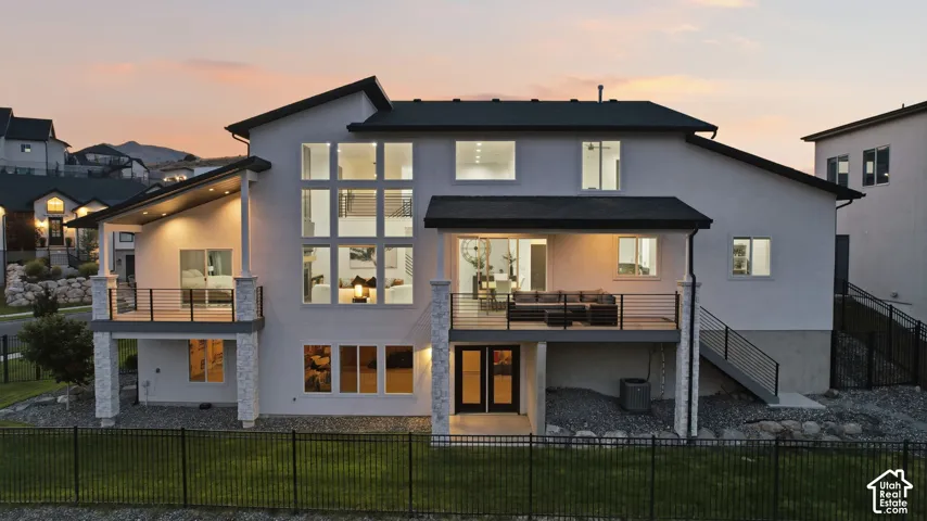Multi-level exterior with extensive glazing, two balconies with black railings, and a walk-out lower level