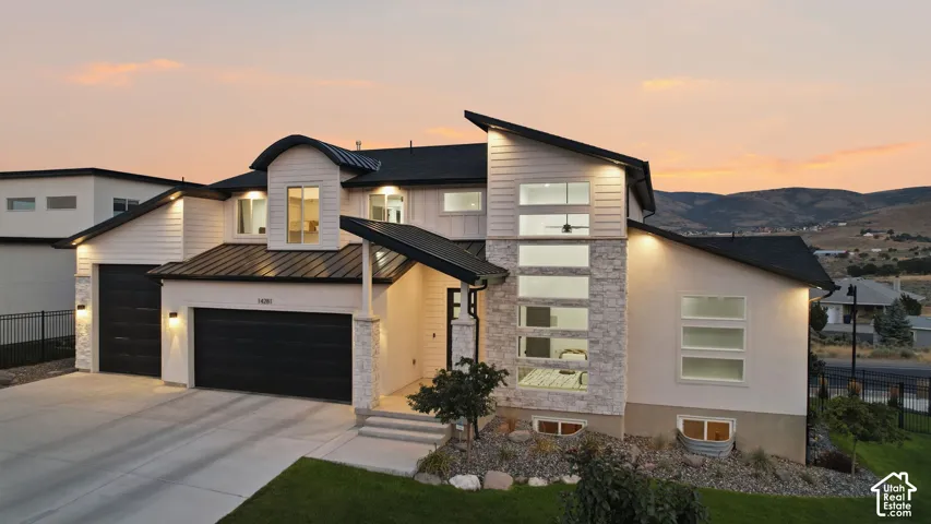 Modern architectural design featuring white siding, stone accents, and a black metal roof