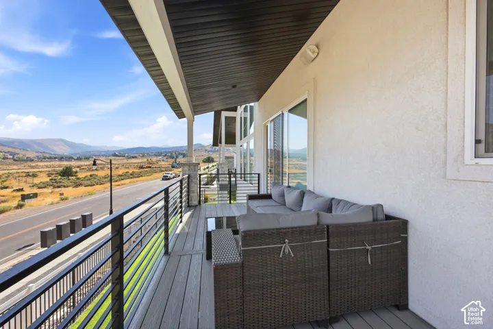 Expansive outdoor deck with composite decking, modern black railing, stucco exterior, and sliding glass doors