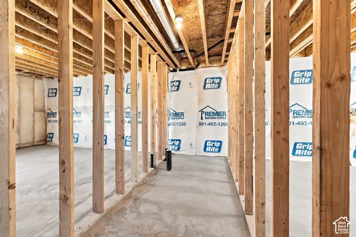 Unfinished basement area with exposed wood framing, concrete flooring, and visible insulation wrapping