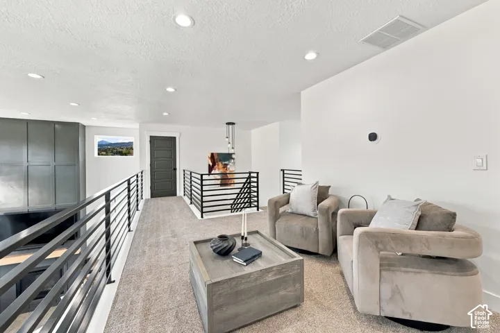 Carpeted loft area featuring recessed lighting, a modern horizontal railing system, a paneled door, and a horizontal window