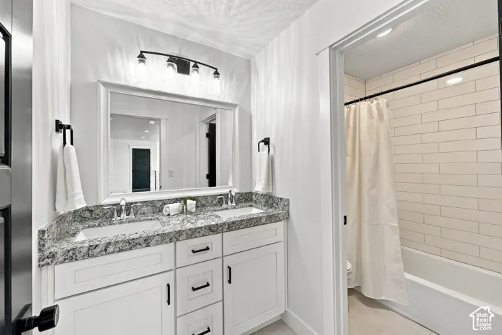 Double vanity with integrated sinks, speckled countertop, and white cabinetry