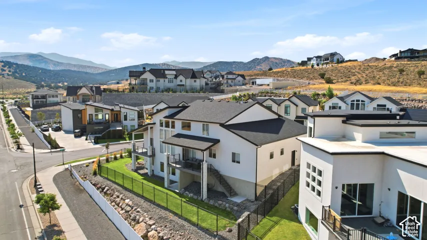 Contemporary architecture featuring a white exterior, multiple balconies, a black shingle roof, and a manicured lawn