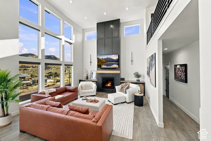 Two-story living area featuring a fireplace with built-in cabinetry, expansive floor-to-ceiling windows, and wood-finish flooring