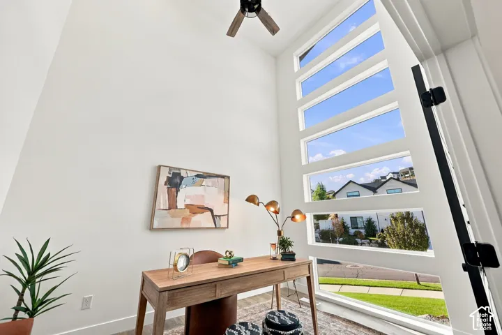 Vaulted ceilings with a ceiling fan, a wall of rectangular windows, and white walls