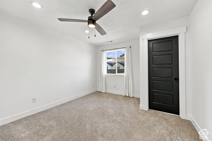 Recessed lighting, ceiling fan with light fixture, carpeted flooring, window with white trim, and a paneled interior door