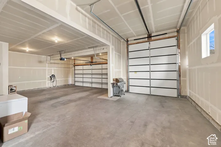 Spacious garage featuring two overhead doors, exposed framing, a window, and a concrete floor