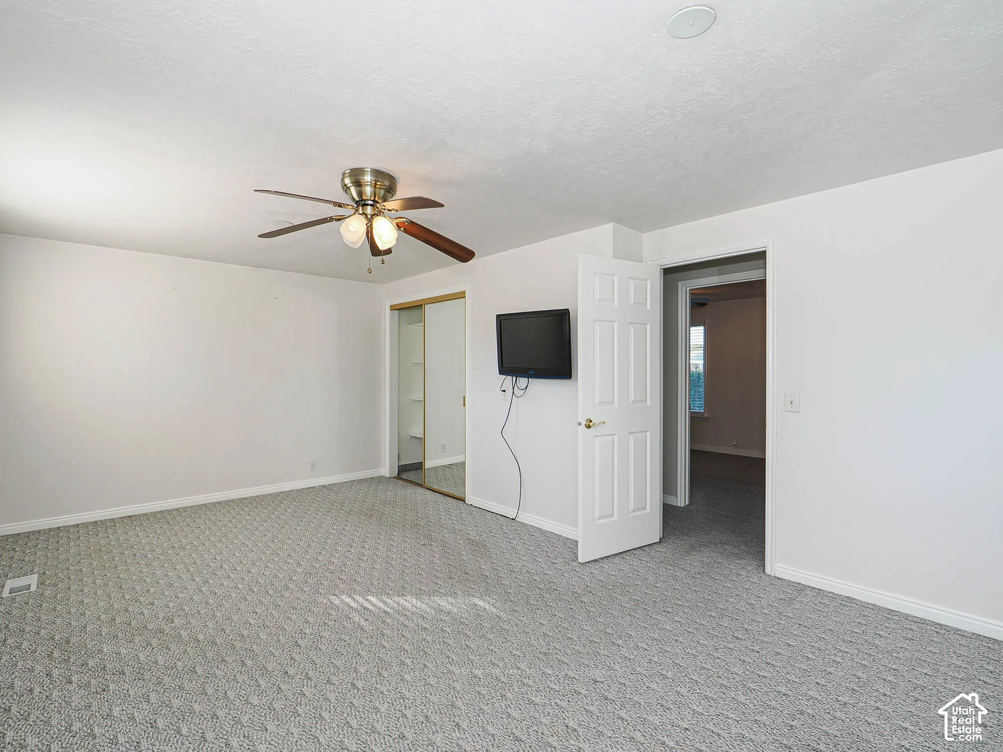 Ceiling fan with light fixture, carpeted flooring, white walls, white trim, mirrored closet doors