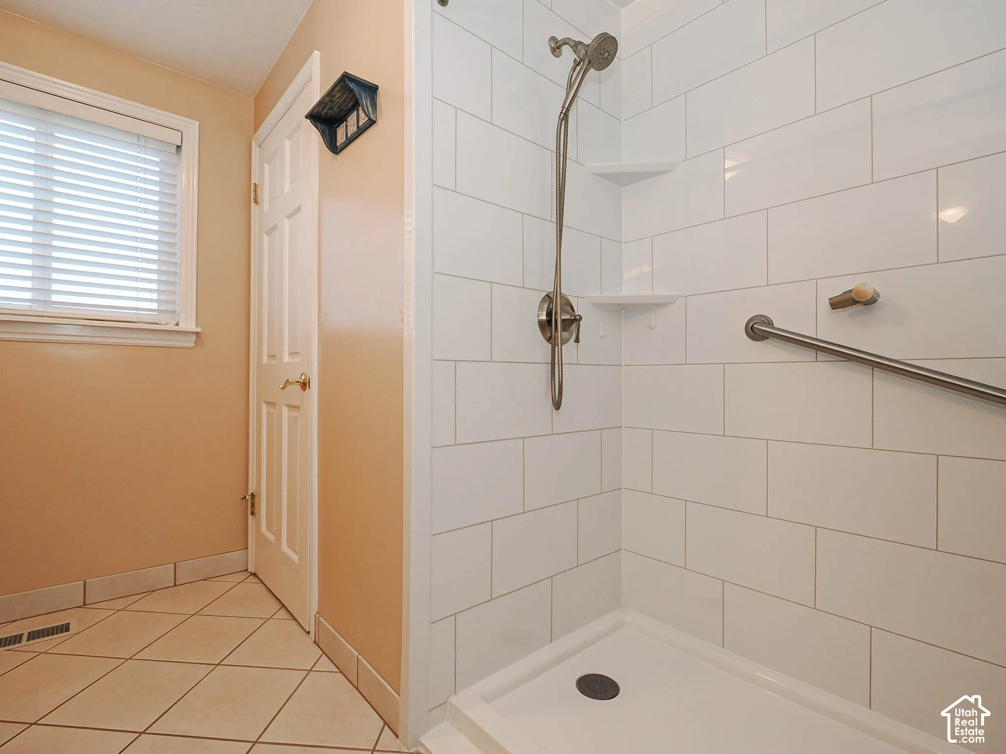 Shower with subway tile surround, integrated shelving, and a handheld shower fixture