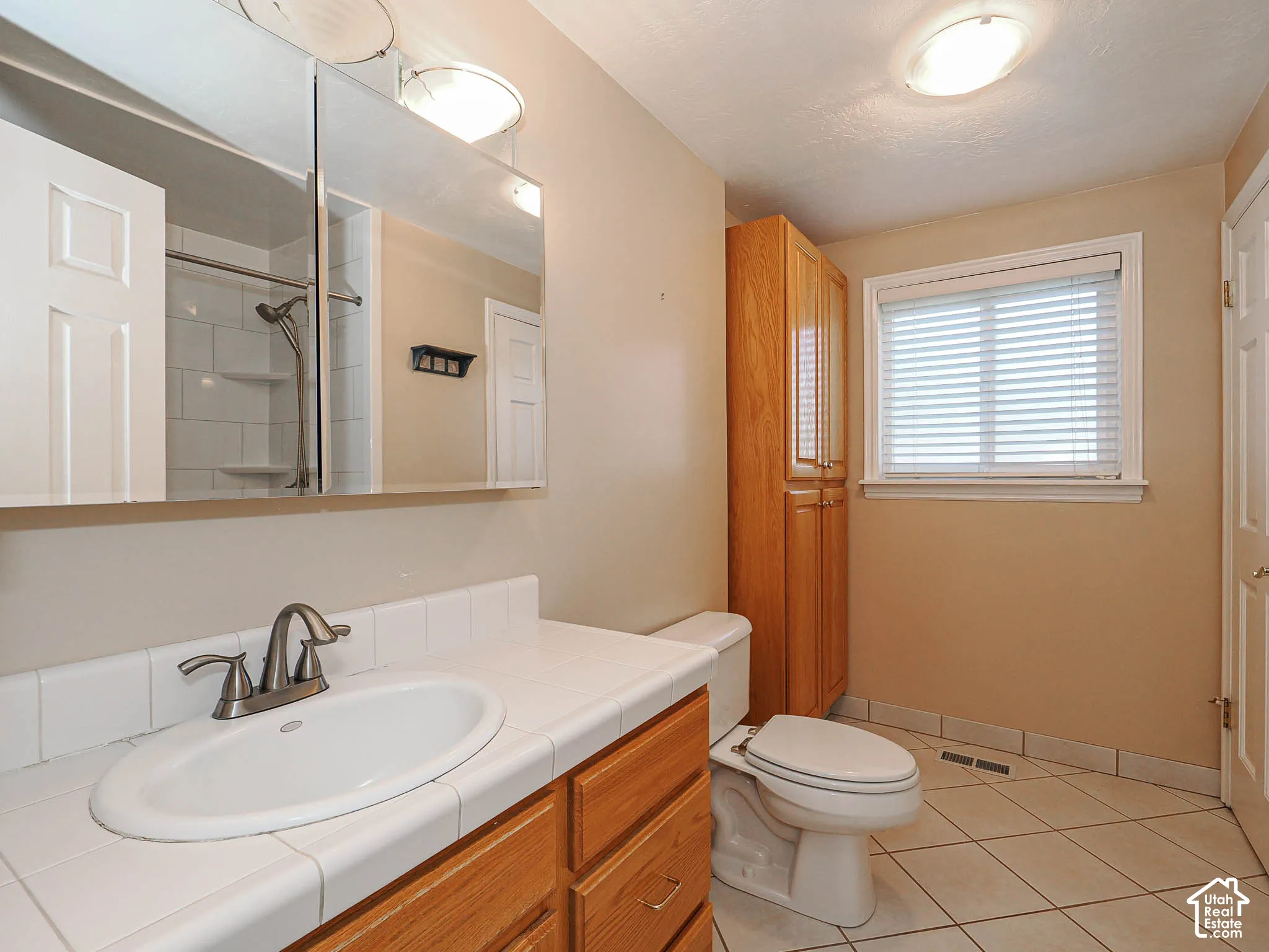 Wood-finish vanity with an integrated sink and tiled countertop