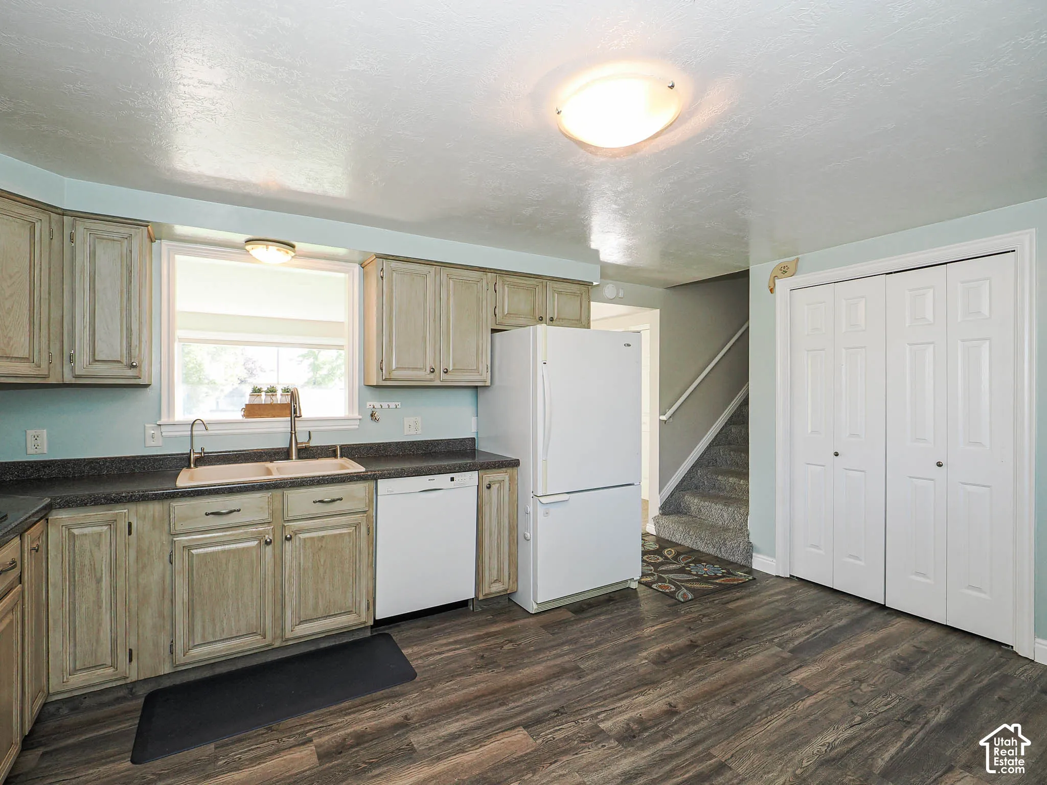 Wood-finish flooring, light-toned cabinetry, double-basin sink, built-in dishwasher, and a refrigerator