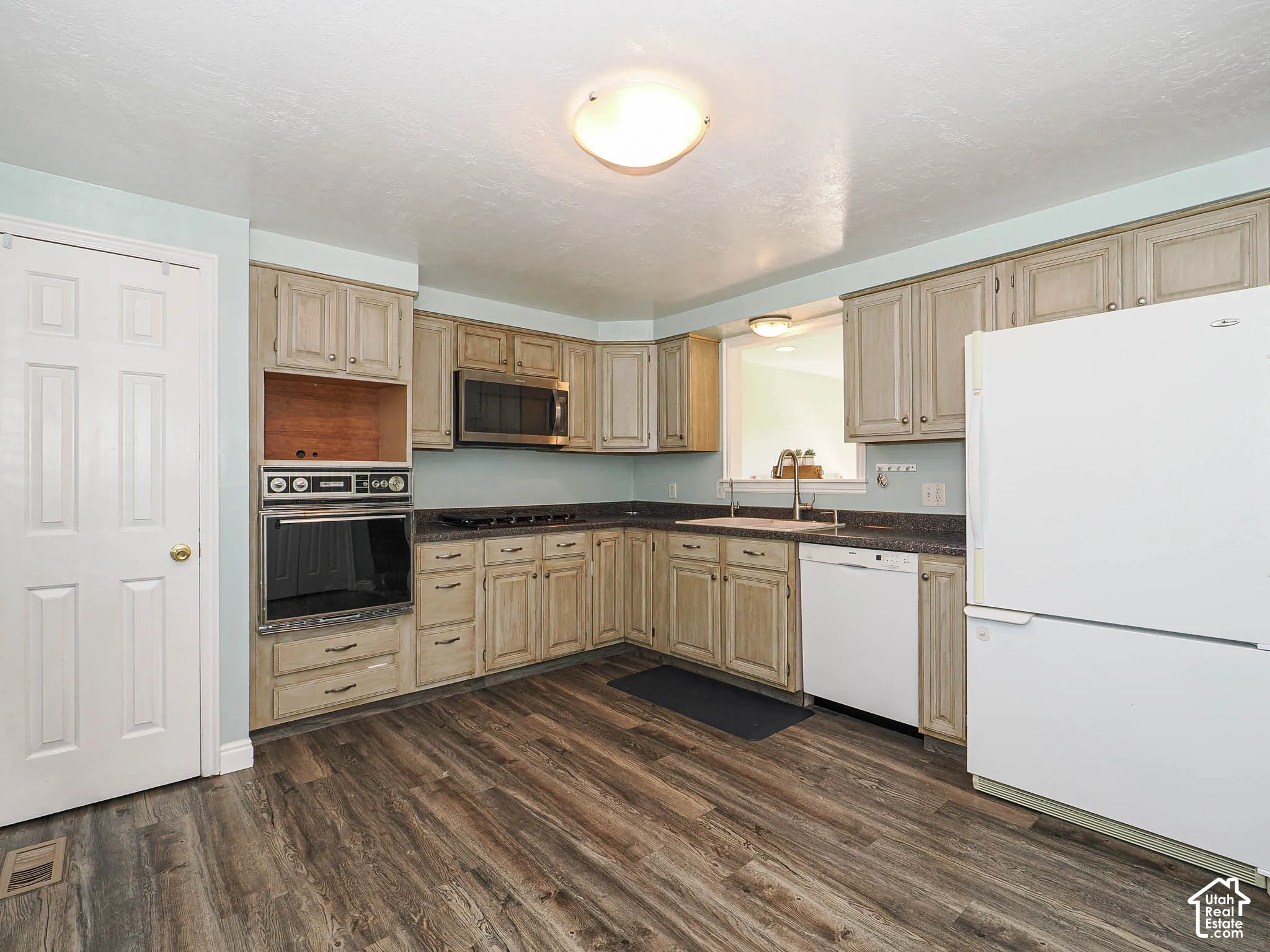 Kitchen featuring wood-finish flooring, built-in wall oven, built-in microwave, and ample cabinetry