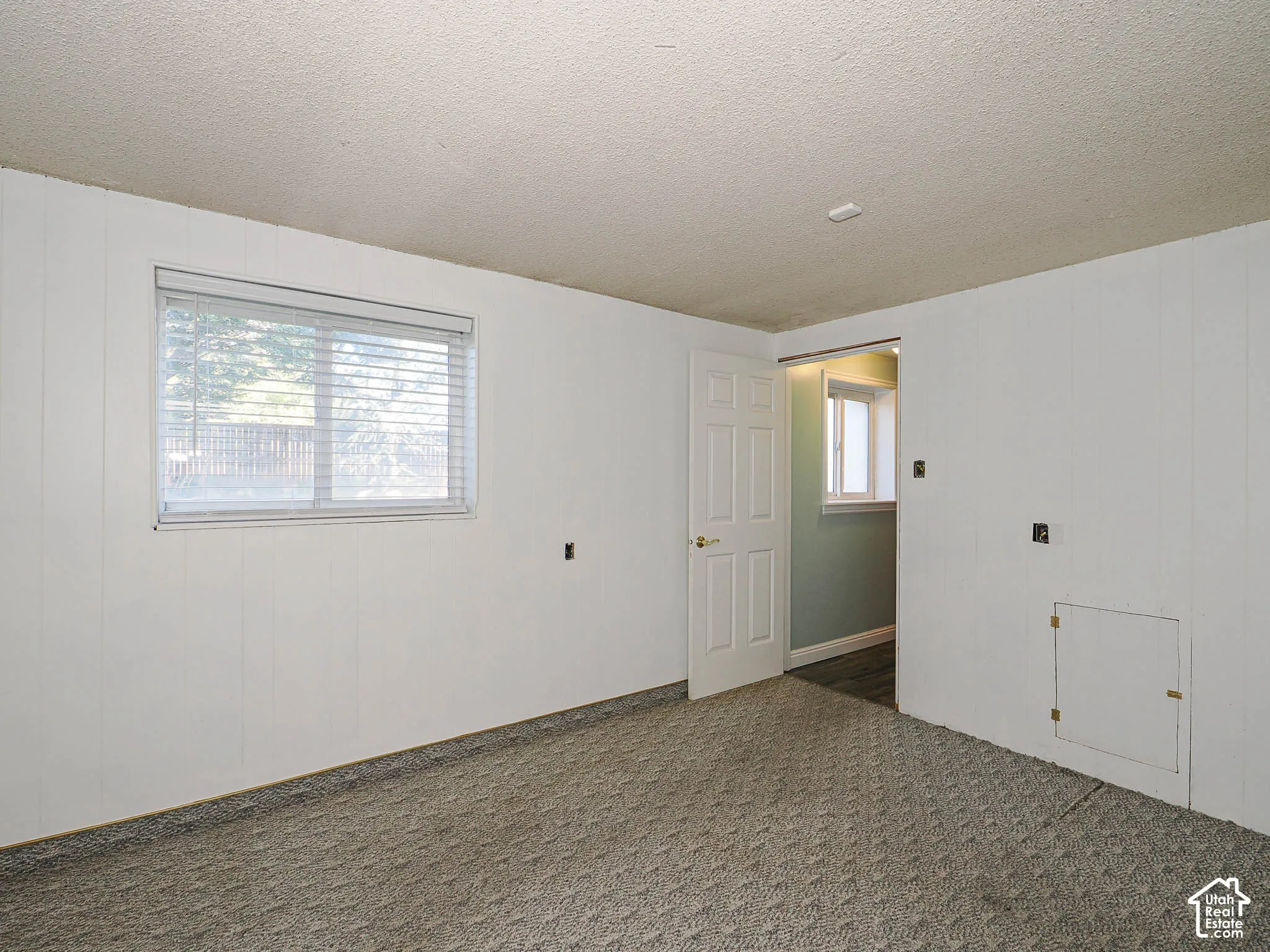 Wall-to-wall carpeting, paneled walls, and a window with blinds