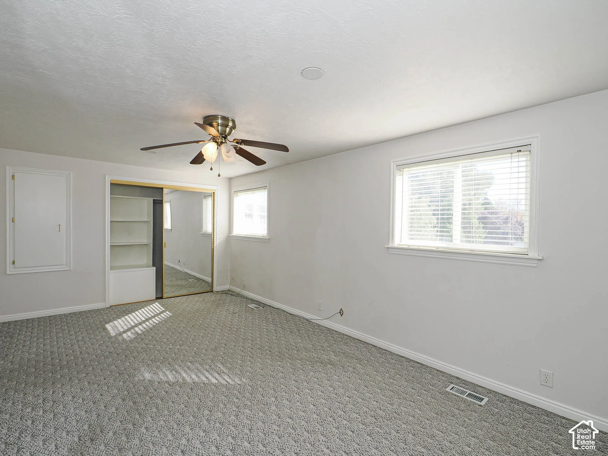 Recessed lighting, ceiling fan, two windows with blinds, mirrored sliding closet doors, and built-in shelving