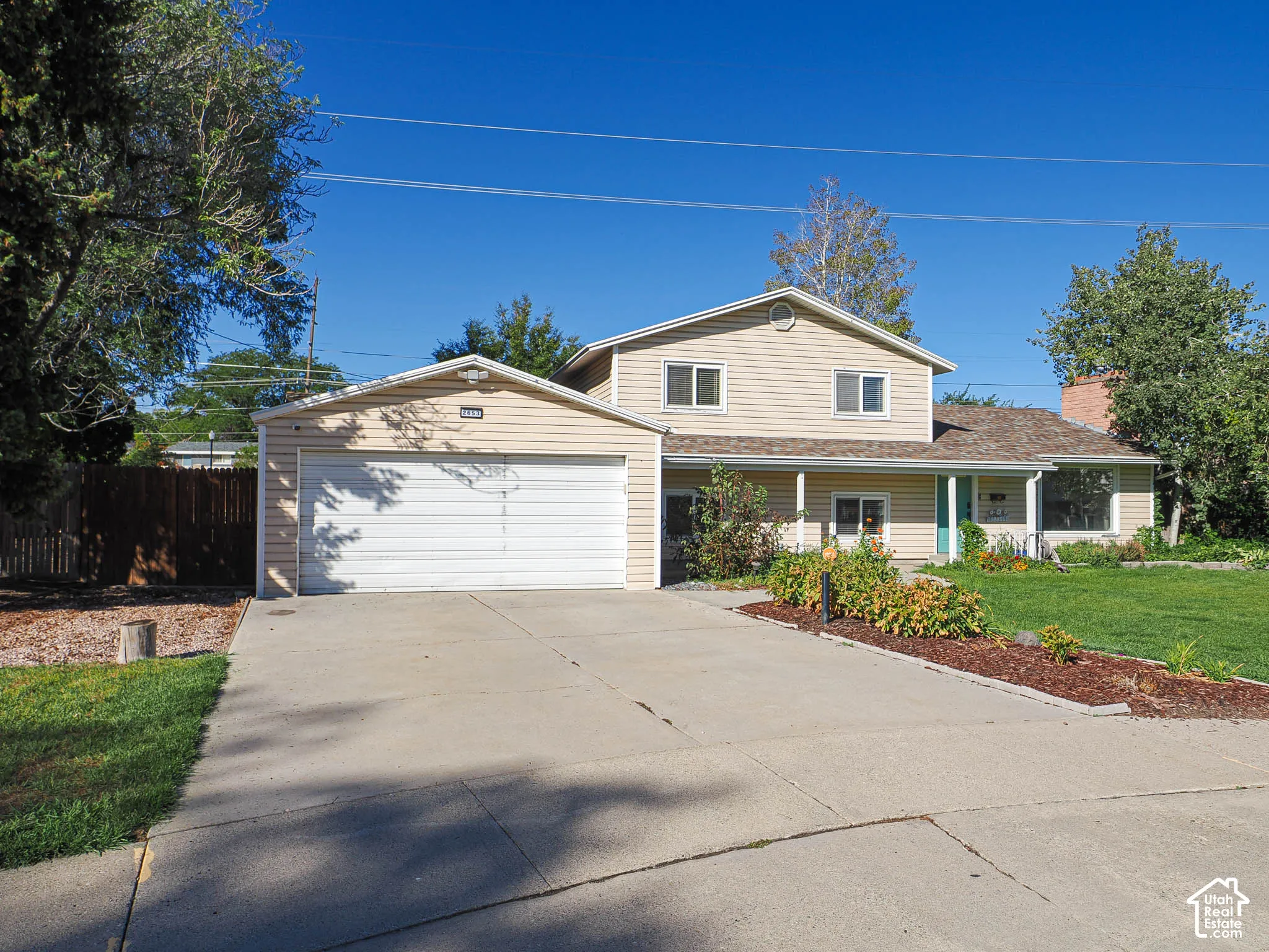 Light-colored siding exterior with a two-car garage, concrete driveway, and front lawn