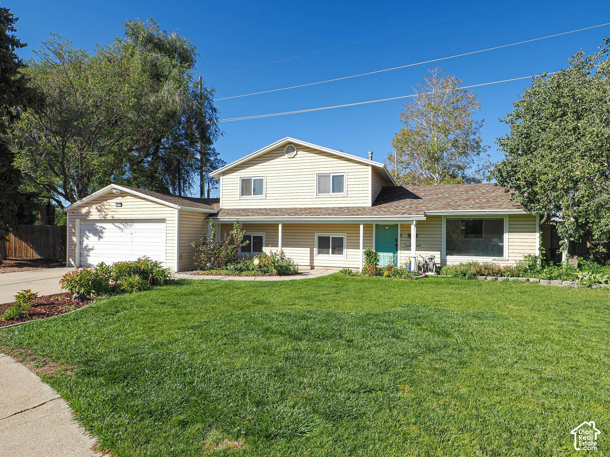 Two-story exterior with siding, attached garage, covered front porch, and expansive front lawn